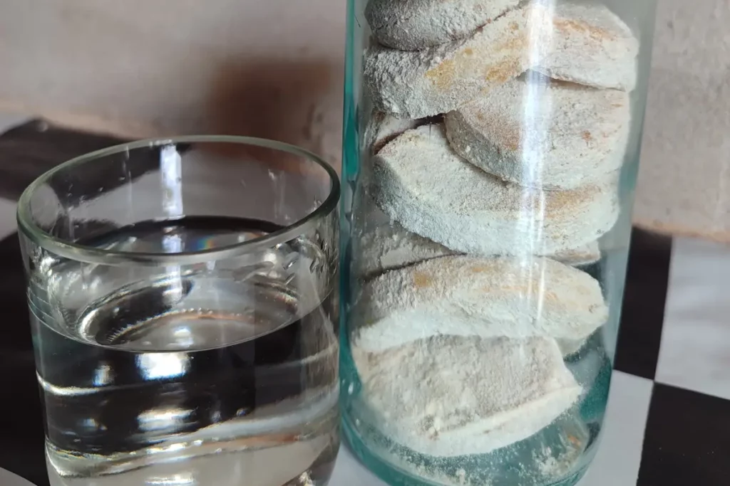 Ein Glas Wasser neben einem Glasbehälter mit Keksen.