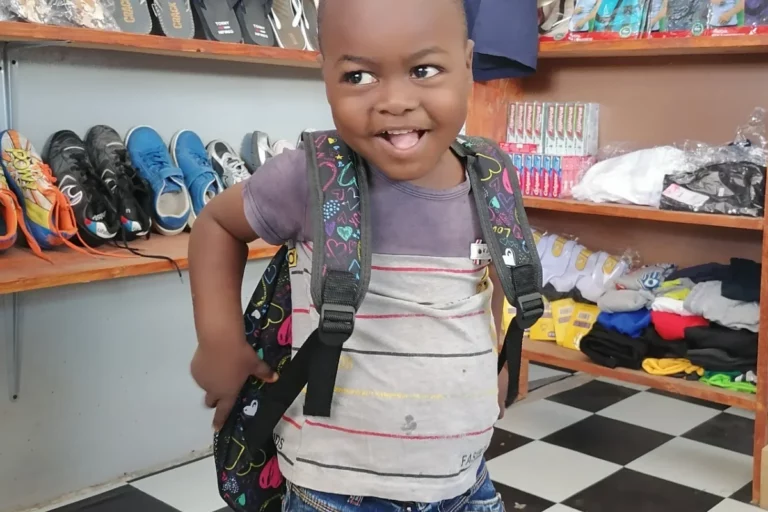 Ein lachendes Kind trägt einen neuen Rucksack in einem SwopShop.