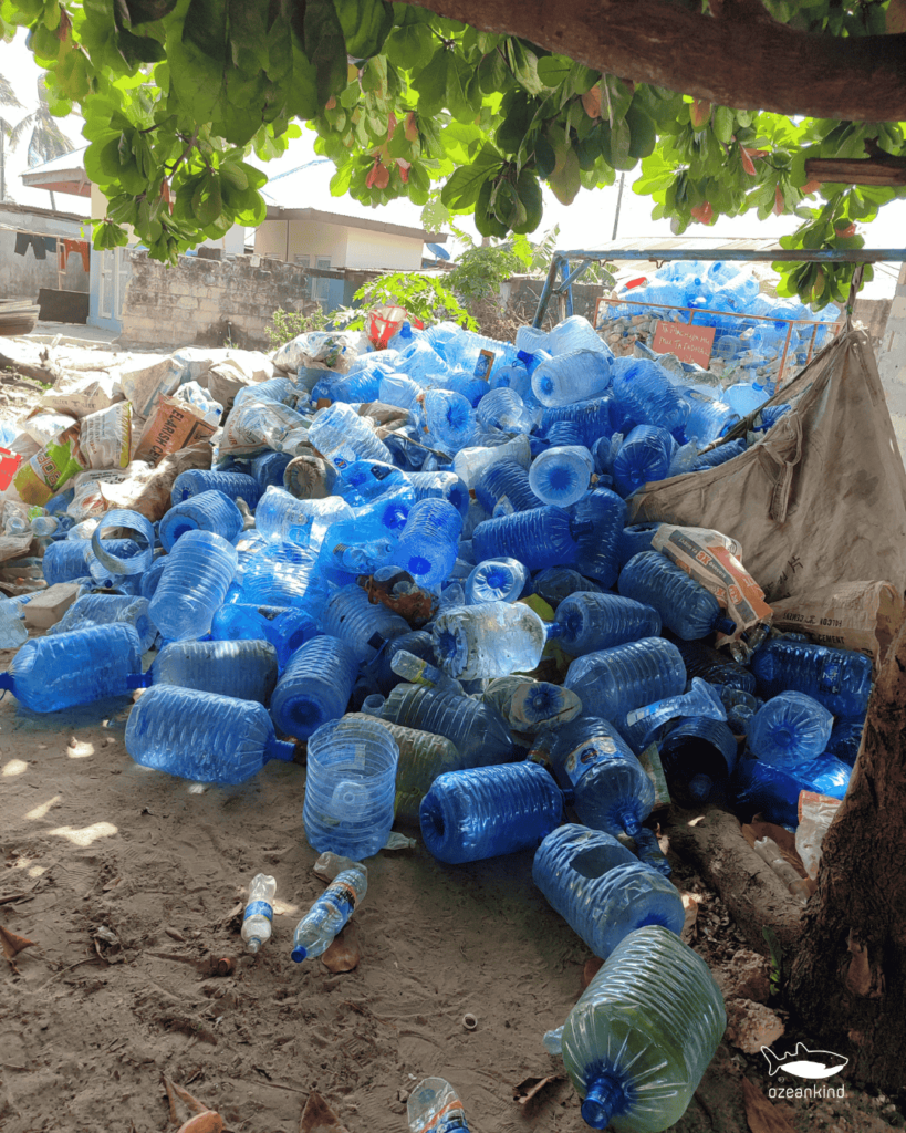 Ein großer Haufen gesammelter blauer Plastikflaschen unter einem Baum auf Sansibar.