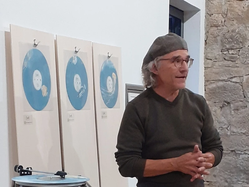 Ein Mann spricht bei einer Kunstausstellung vor gerahmten Bildern.